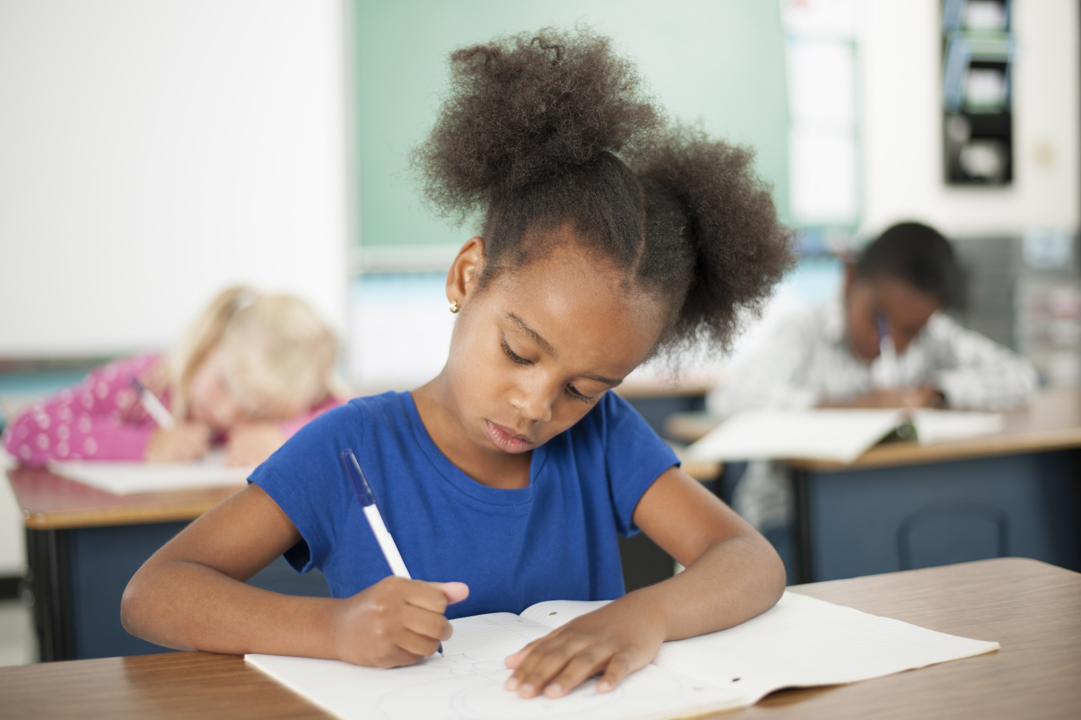 an older girl writing with a pencil who is 7 to 11 years old