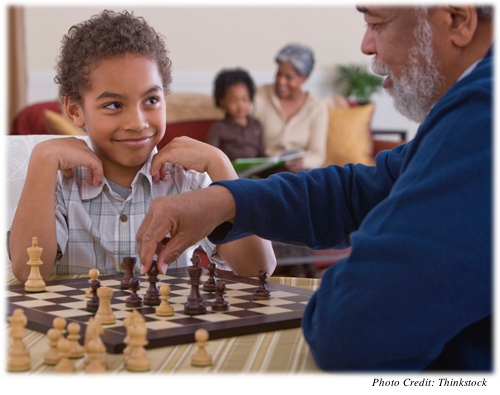 A young boy playing chess with his grandfather